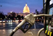 Fuel pump nozzle in the foreground with the illuminated US Capitol dome visible at night