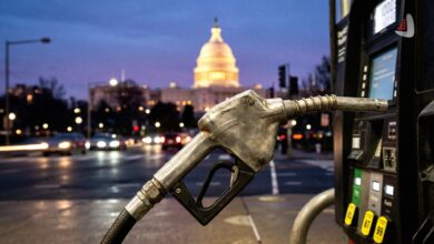 Fuel pump nozzle in the foreground with the illuminated US Capitol dome visible at night
