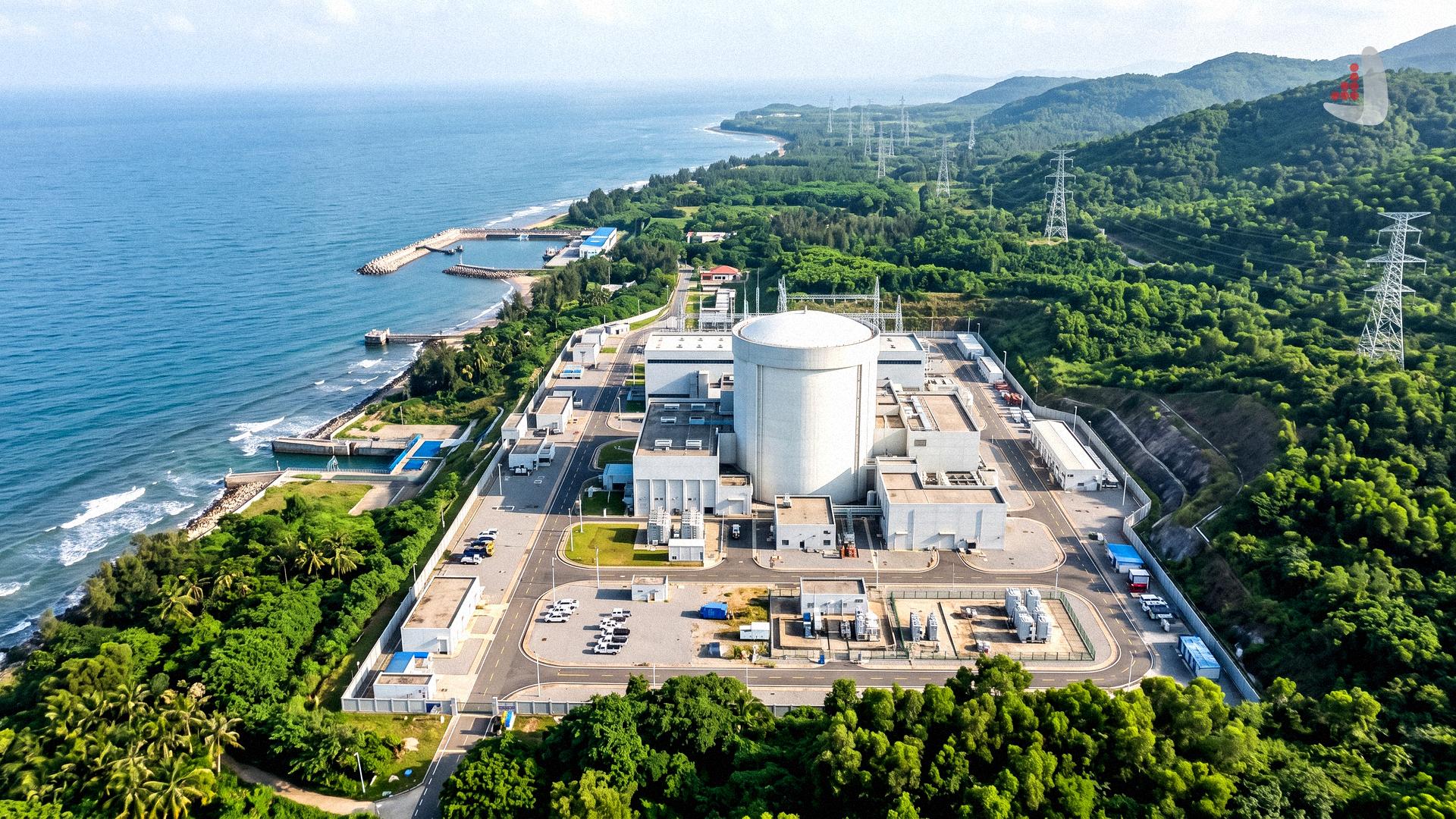 Aerial view of a coastal nuclear power plant facility with a reactor containment dome surrounded by tropical greenery