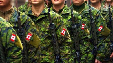 Soldiers of the Canadian Armed Forces, dressed in military uniforms and carrying weapons, moving through an outdoor environment