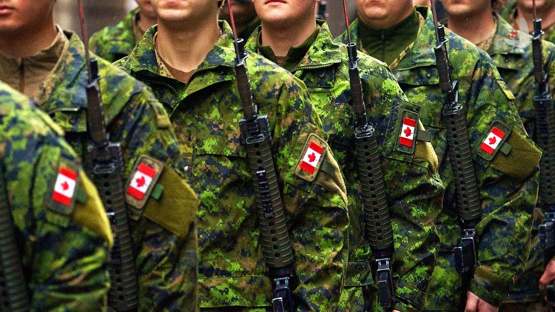 Soldiers of the Canadian Armed Forces, dressed in military uniforms and carrying weapons, moving through an outdoor environment