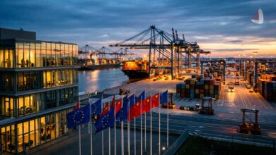 Flags of the European Union and China flying at a busy industrial shipping port at sunset