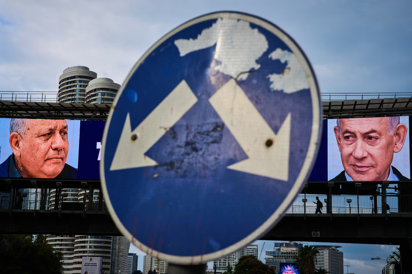 Pedestrian silhouette walking past an election billboard featuring Benjamin Netanyahu and Gadi Eisenkot
