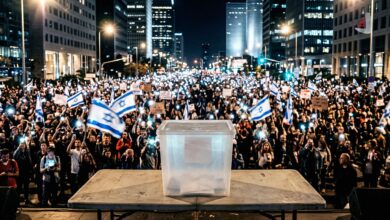 Clear ballot box on a table in front of a massive crowd of anti-government protesters in Tel Aviv
