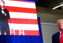 Donald Trump speaks at an election rally in Michigan, with an image of Abdul El-Sayed, the Democratic candidate for the U.S. Senate, displayed on the screen behind him