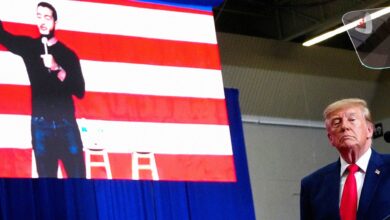 Donald Trump speaks at an election rally in Michigan, with an image of Abdul El-Sayed, the Democratic candidate for the U.S. Senate, displayed on the screen behind him