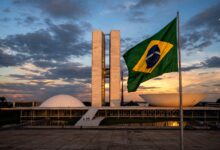 The National Congress of Brazil building at dusk with the Brazilian flag flying in the foreground