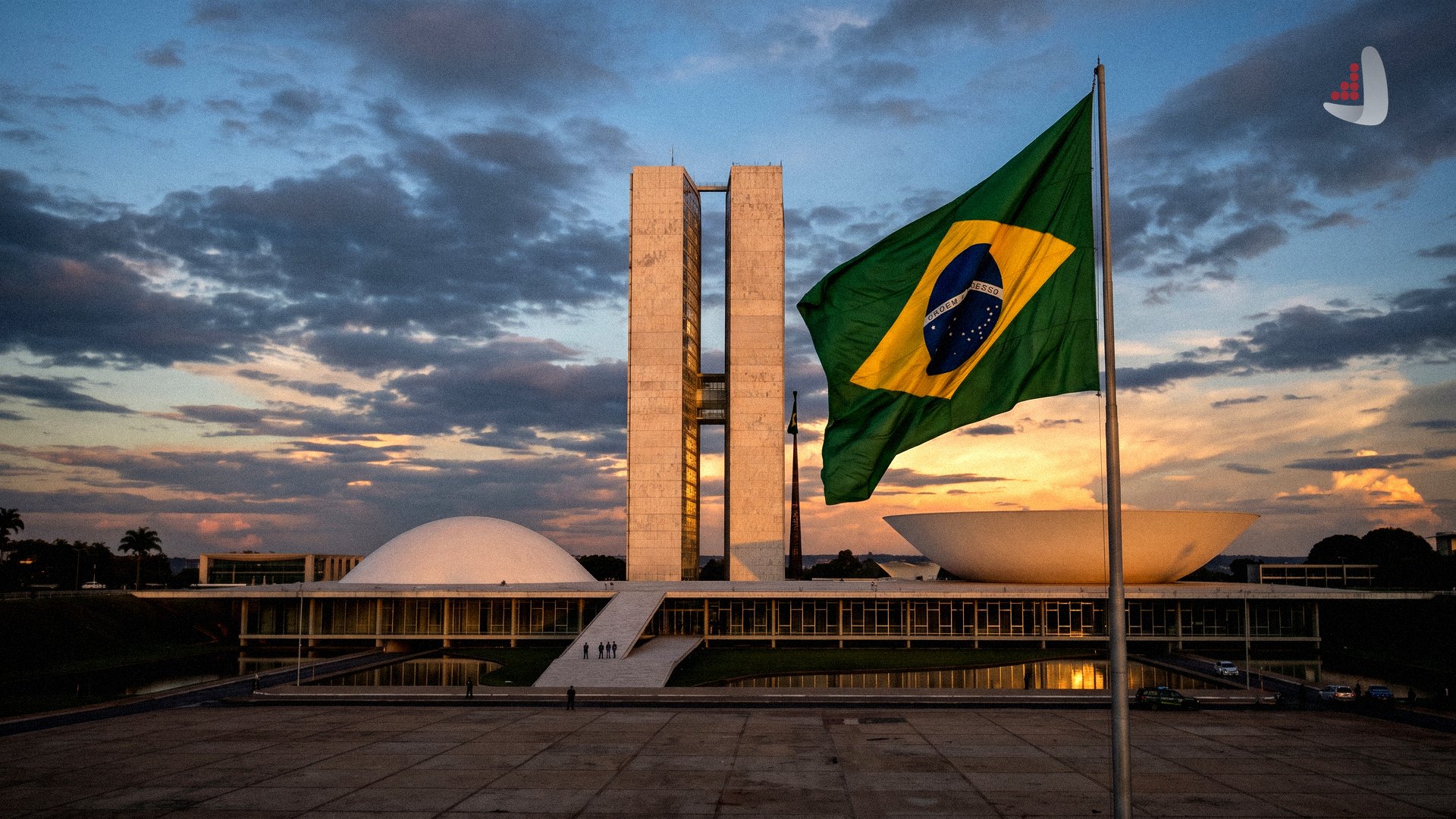 The National Congress of Brazil building at dusk with the Brazilian flag flying in the foreground