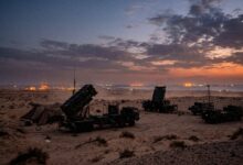 Patriot missile defense systems deployed in a coastal desert area at sunset